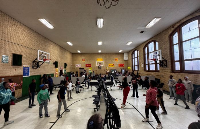  clark students competing in match of volleyball as student spectators watch from sidelines